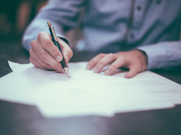 A reviewer marking a written page with a pen